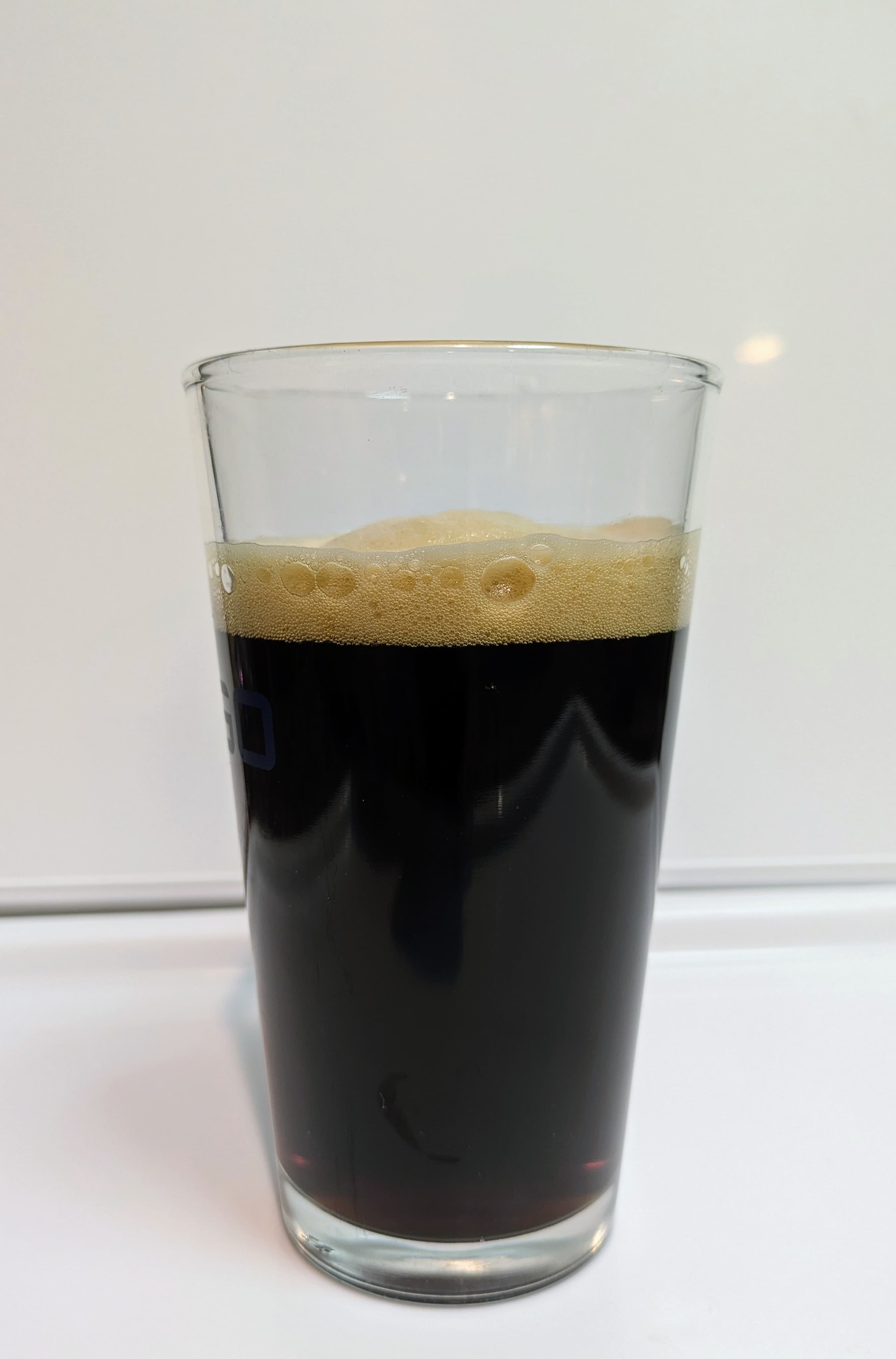 Black beer in a pint glass with a deep tan head
